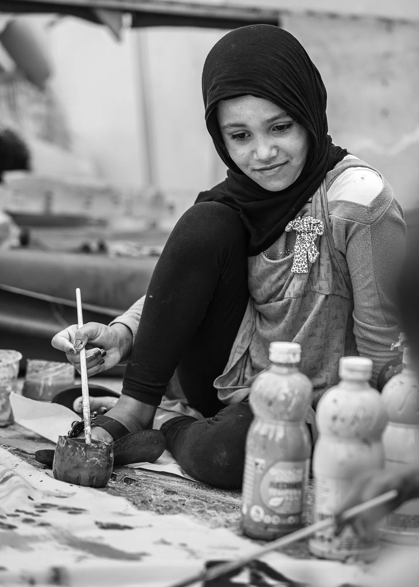 Asal seated during a painting activity, looking toward her work.