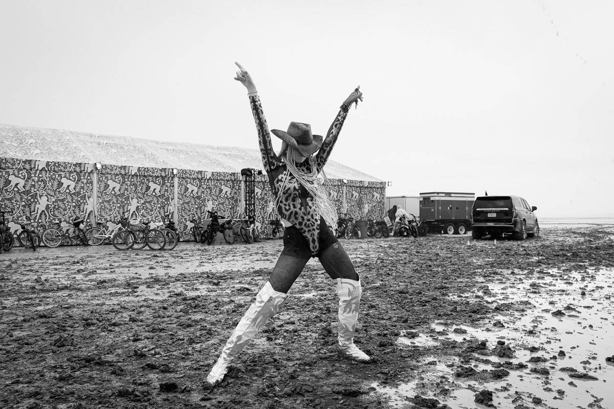 A woman in a cowboy hat stretches her arms to the sky